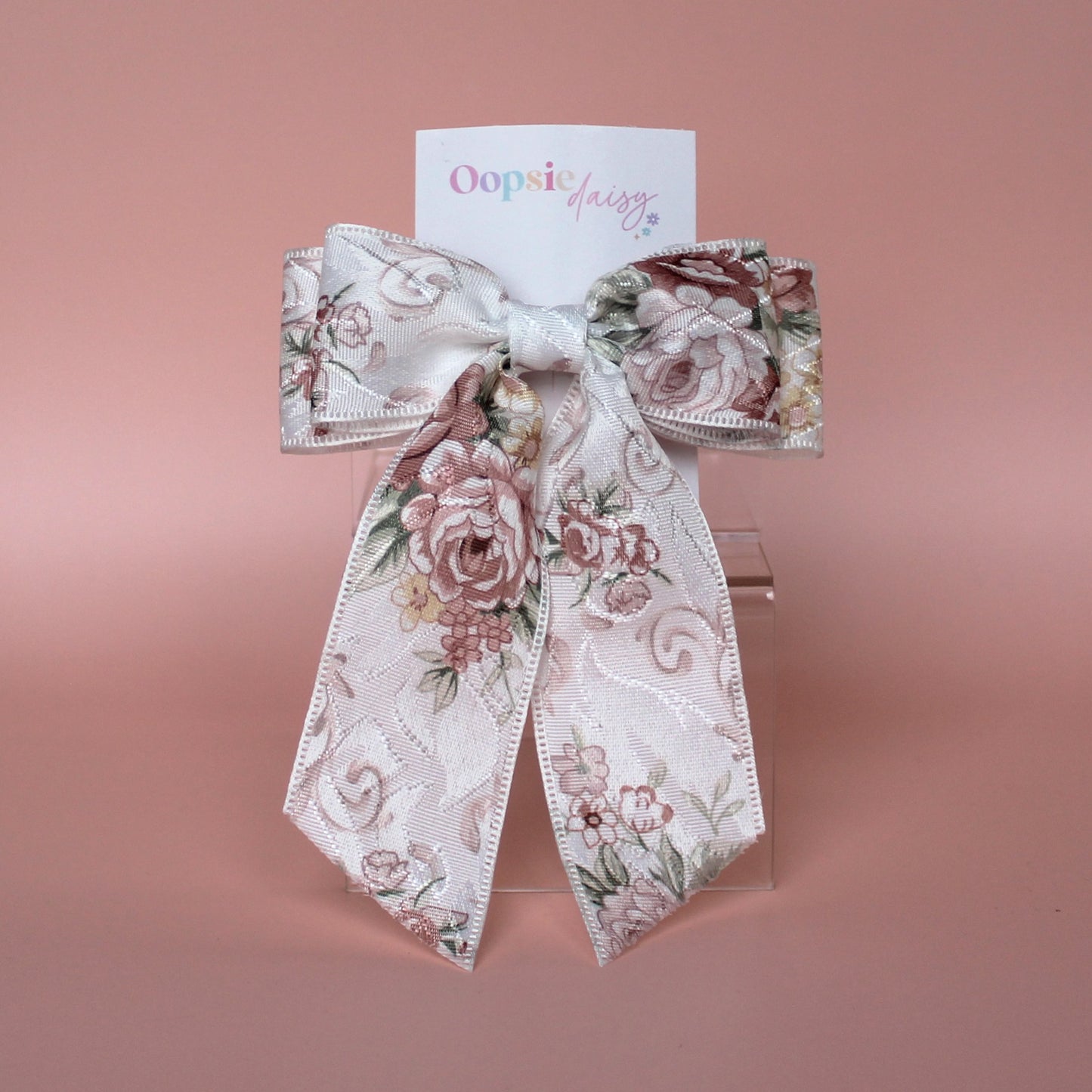Off-white hair bow with peach coloured floral pattern
