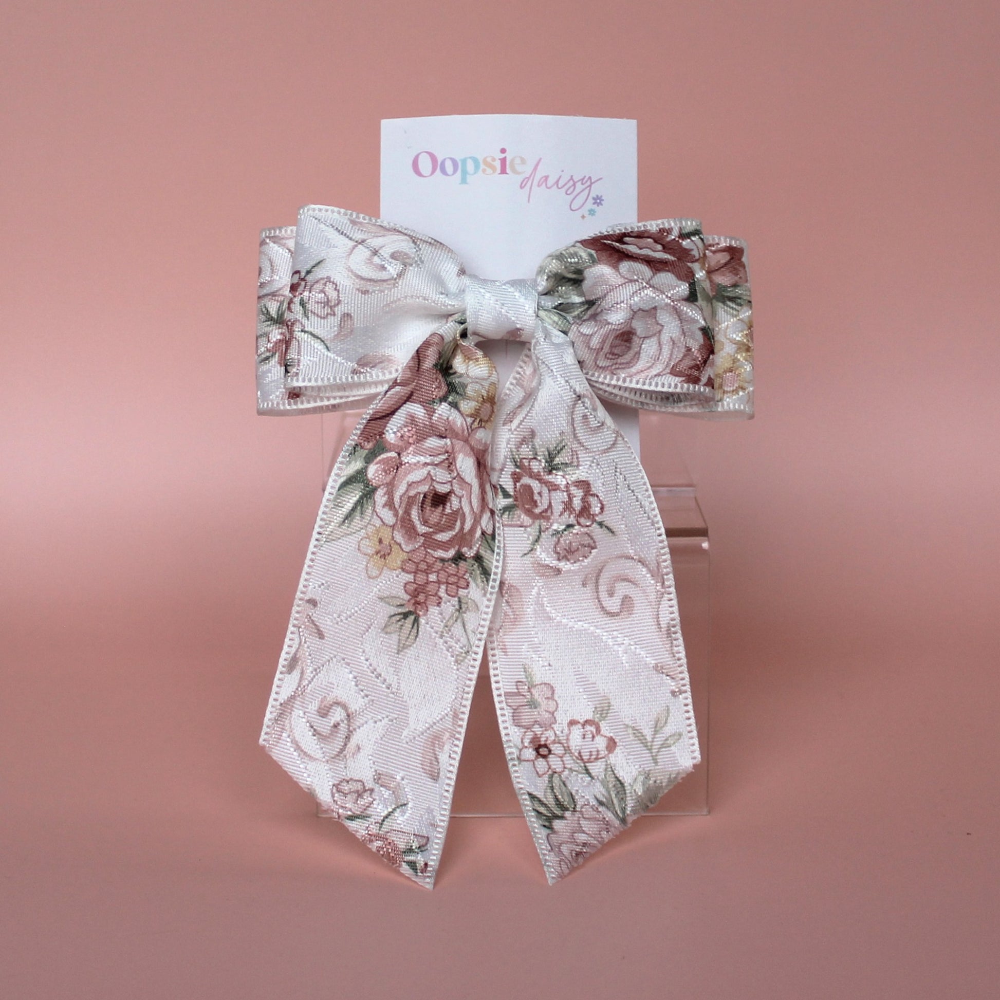 Off-white hair bow with peach coloured floral pattern