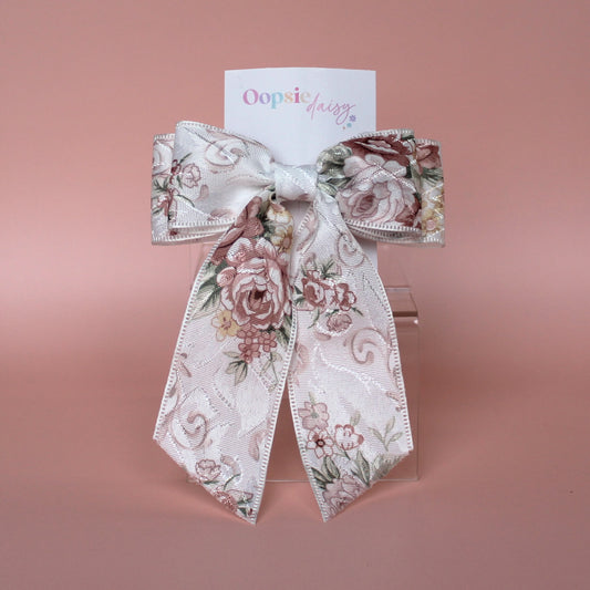 Off-white hair bow with peach coloured floral pattern