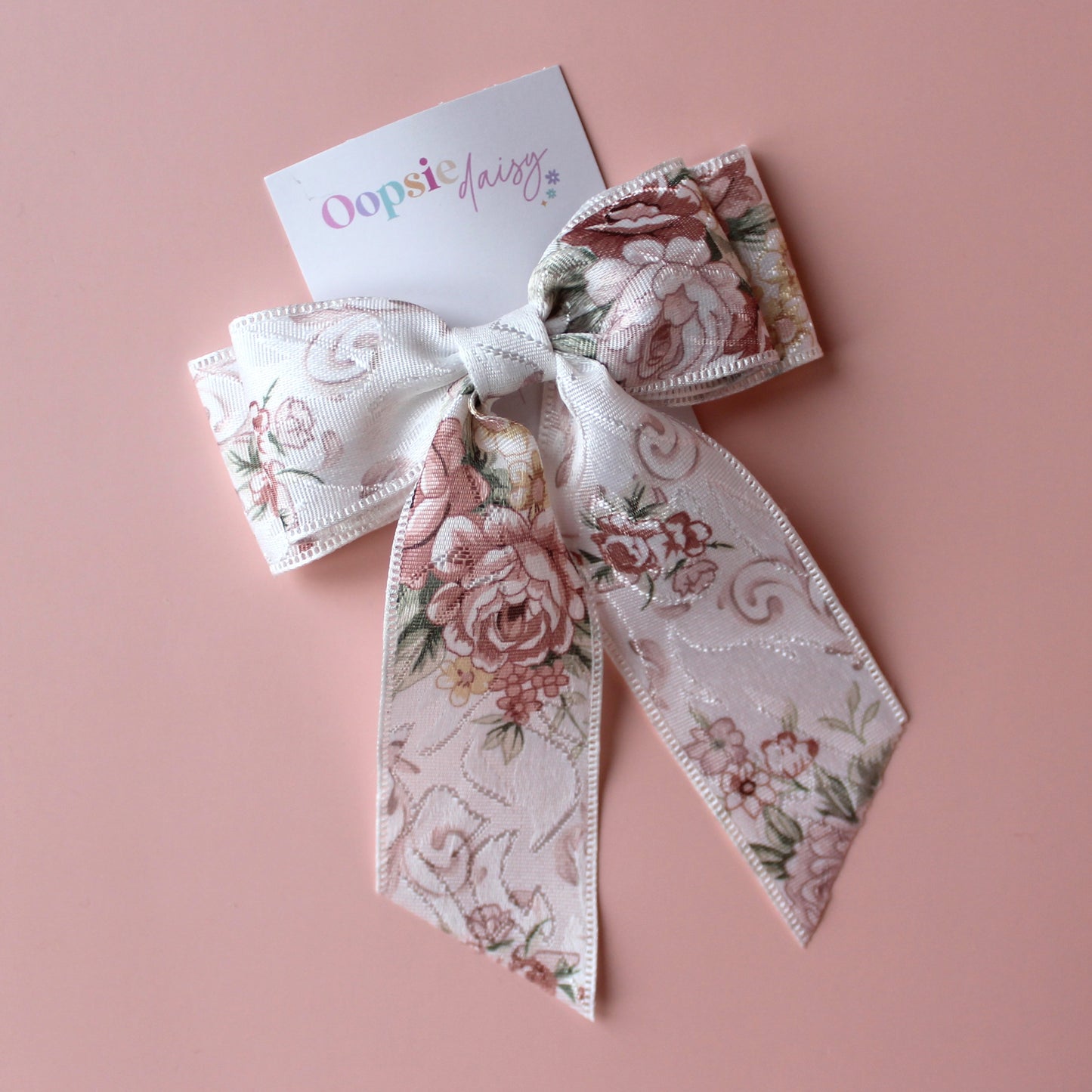 Off-white hair bow with peach coloured floral pattern
