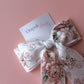 Off-white hair bow with peach coloured floral pattern