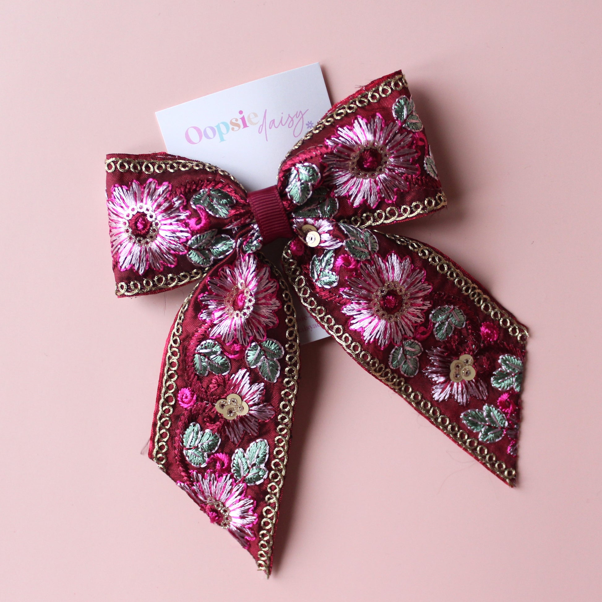 Deep red hair bow with embroidered floral pattern and sequins in gold, light pink and green