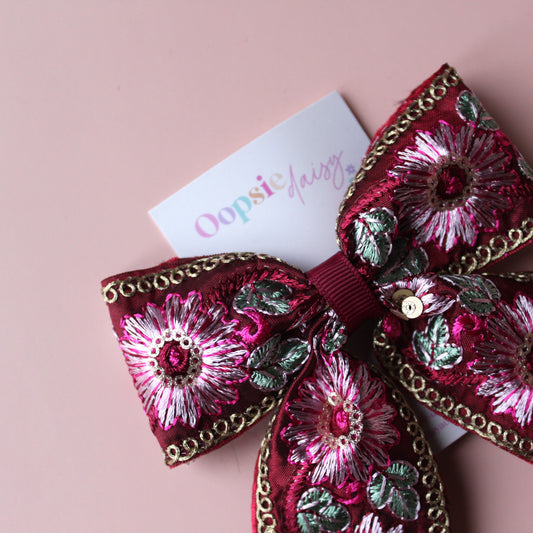 Deep red hair bow with embroidered floral pattern and sequins in gold, light pink and green