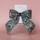 Teal hair bow with gold, pink and burgundy embroidered floral pattern with gold sequins