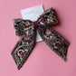 Black hair bow with gold and burgundy embroidered floral pattern