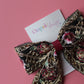 Black hair bow with gold and burgundy embroidered floral pattern