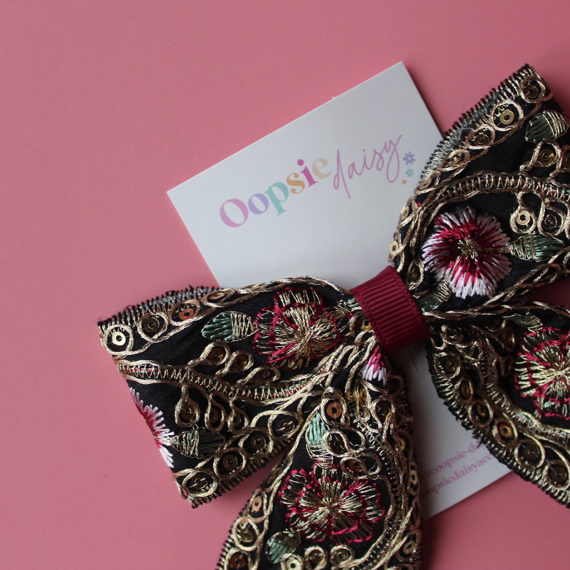Black hair bow with gold and burgundy embroidered floral pattern