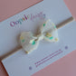 Sheer cream bow on baby headband with dainty yellow-cream and green flowers