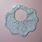 Scallop baby bib with small ditsy floral pattern. Cream background with pink flowers