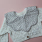 Scallop baby bib with small ditsy floral pattern. Cream background with pink flowers