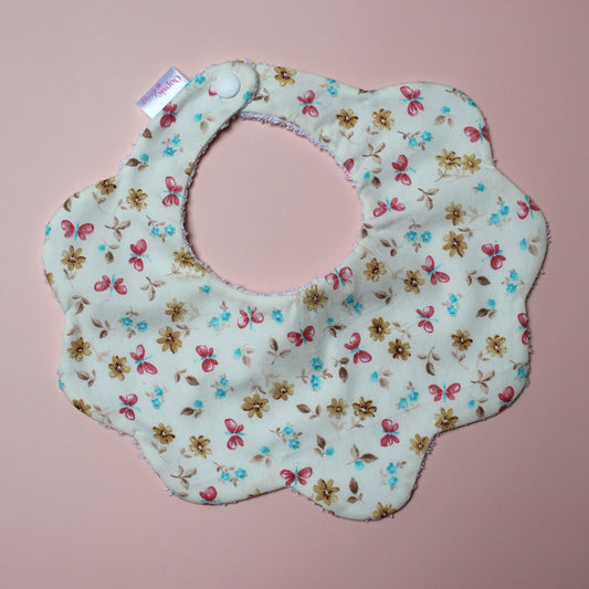 Scallop baby bib in cream with pink, yellow and blue butterfly and flower pattern