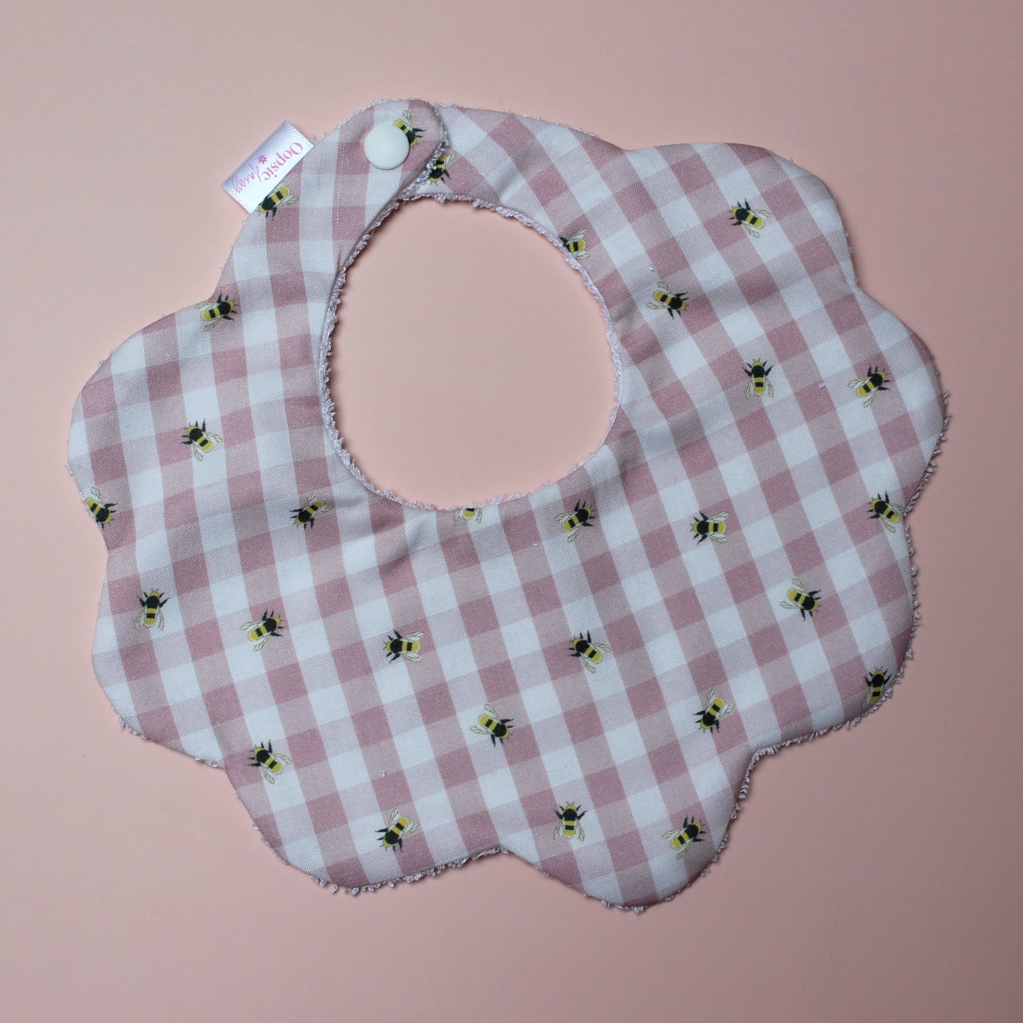 Gingham scallop baby bib in pink and white with little bee pattern.