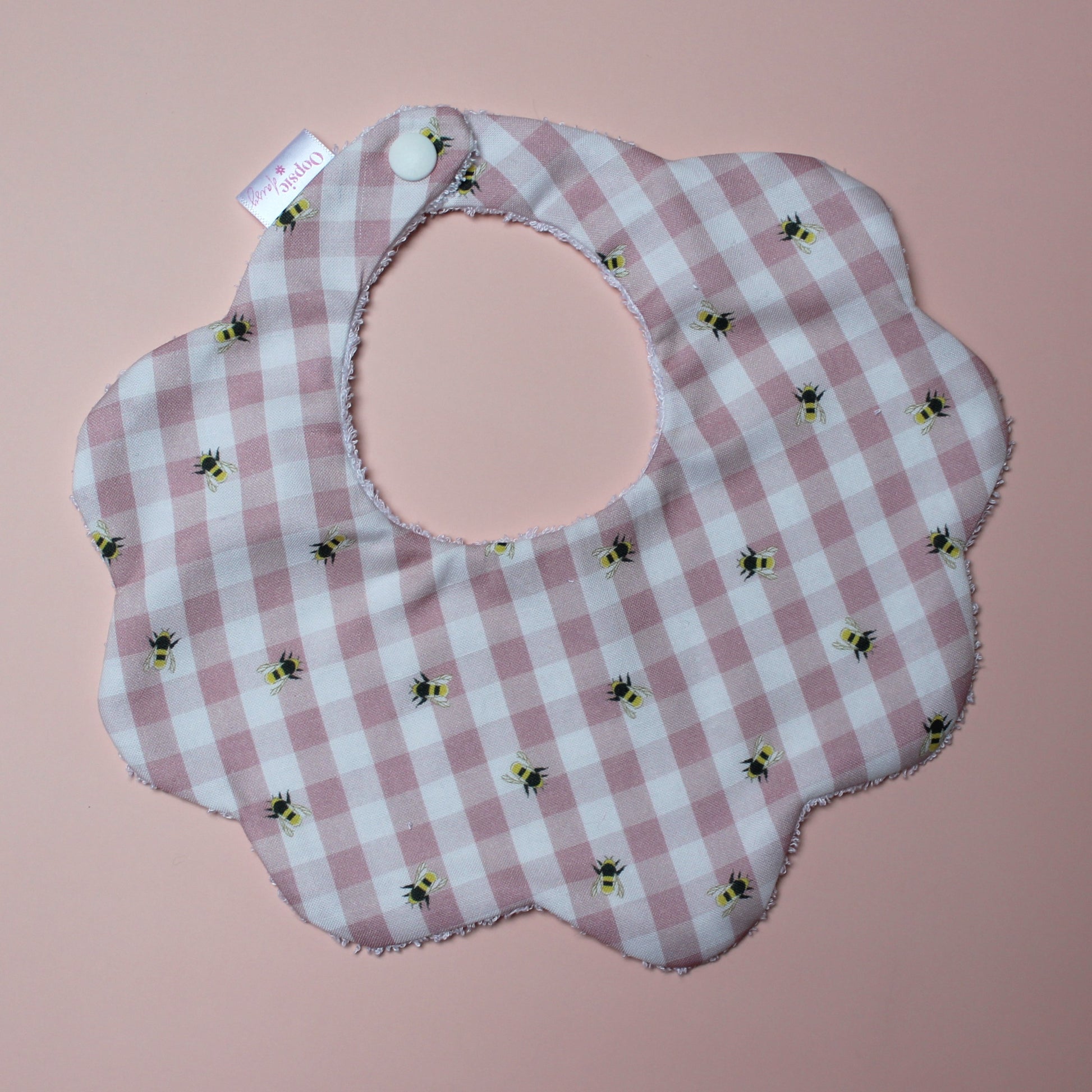 Gingham scallop baby bib in pink and white with little bee pattern.