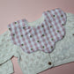 Gingham scallop baby bib in pink and white with little bee pattern.