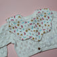 Scallop baby bib in cream with pink, yellow and blue butterfly and flower pattern