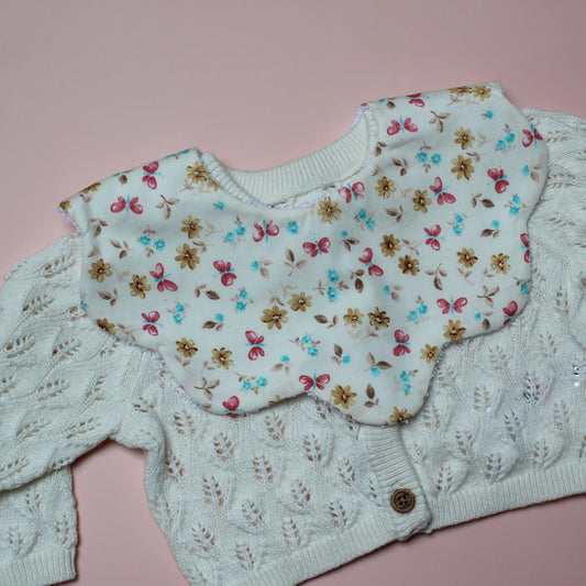 Scallop baby bib in cream with pink, yellow and blue butterfly and flower pattern