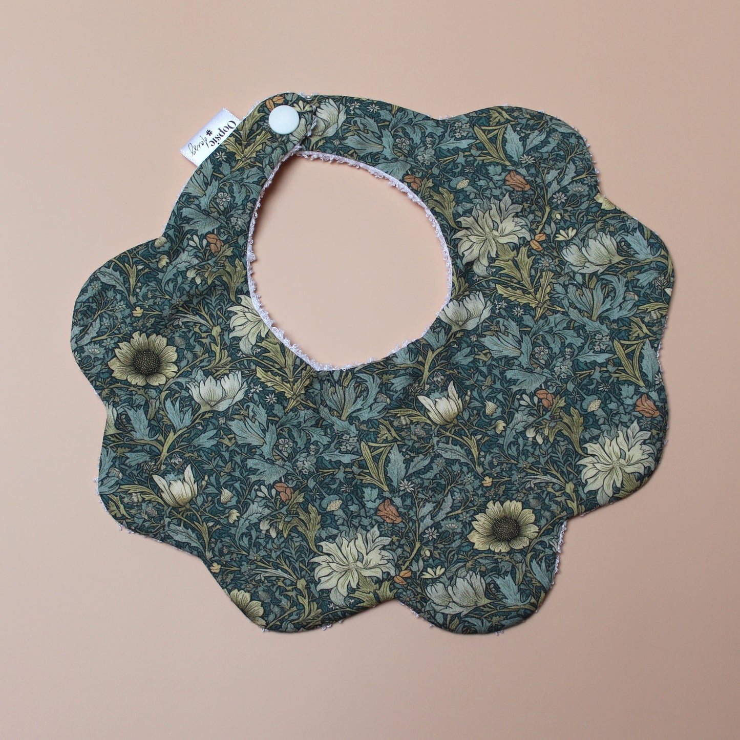 Scallop baby bib in dark green with yellow/ orange all-over floral pattern