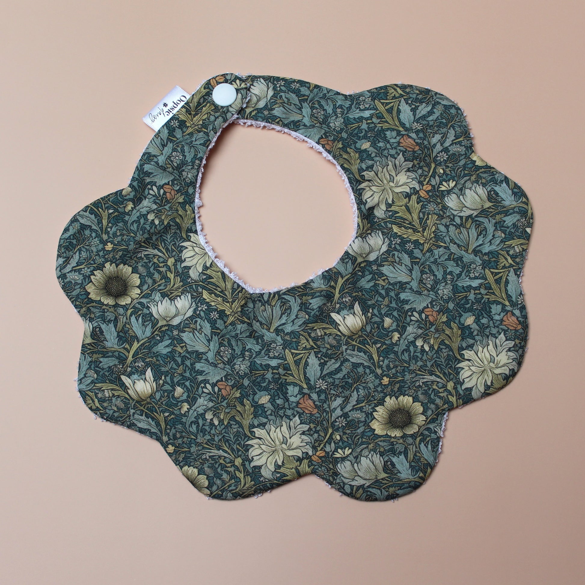 Scallop baby bib in dark green with yellow/ orange all-over floral pattern