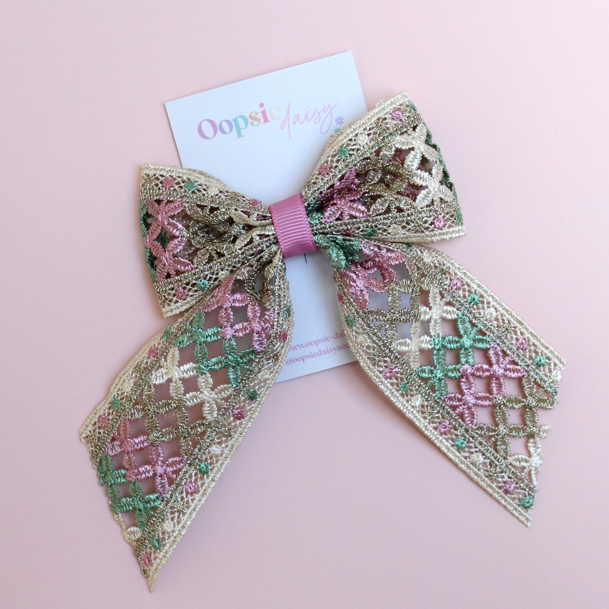 Hair bow with pink, green and gold shimmer embroidered crisscross pattern
