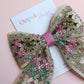 Hair bow with pink, green and gold shimmer embroidered crisscross pattern