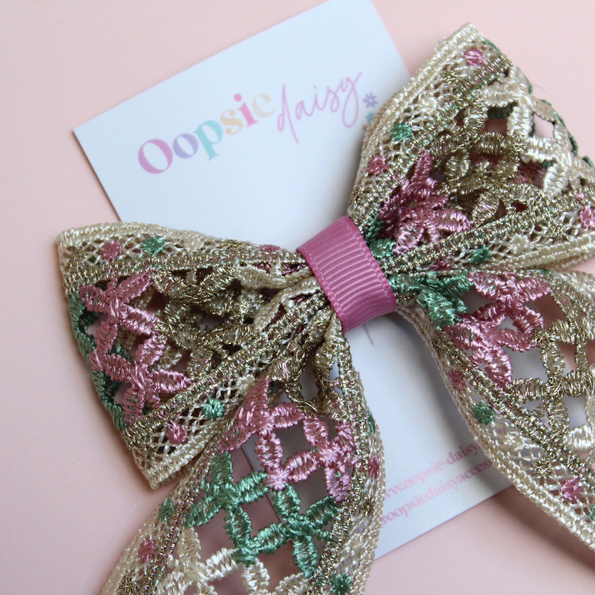 Hair bow with pink, green and gold shimmer embroidered crisscross pattern