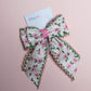 Cream hair bow with pink flowers and pink and green edges
