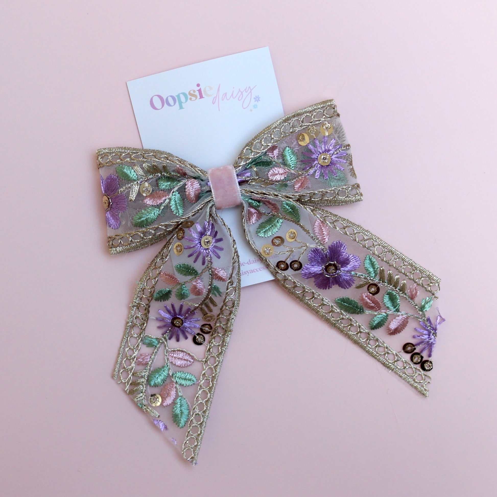 Embroidered hair bow with pink and purple flowers and gold sequins. 