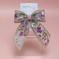 Embroidered hair bow with pink and purple flowers and gold sequins. 