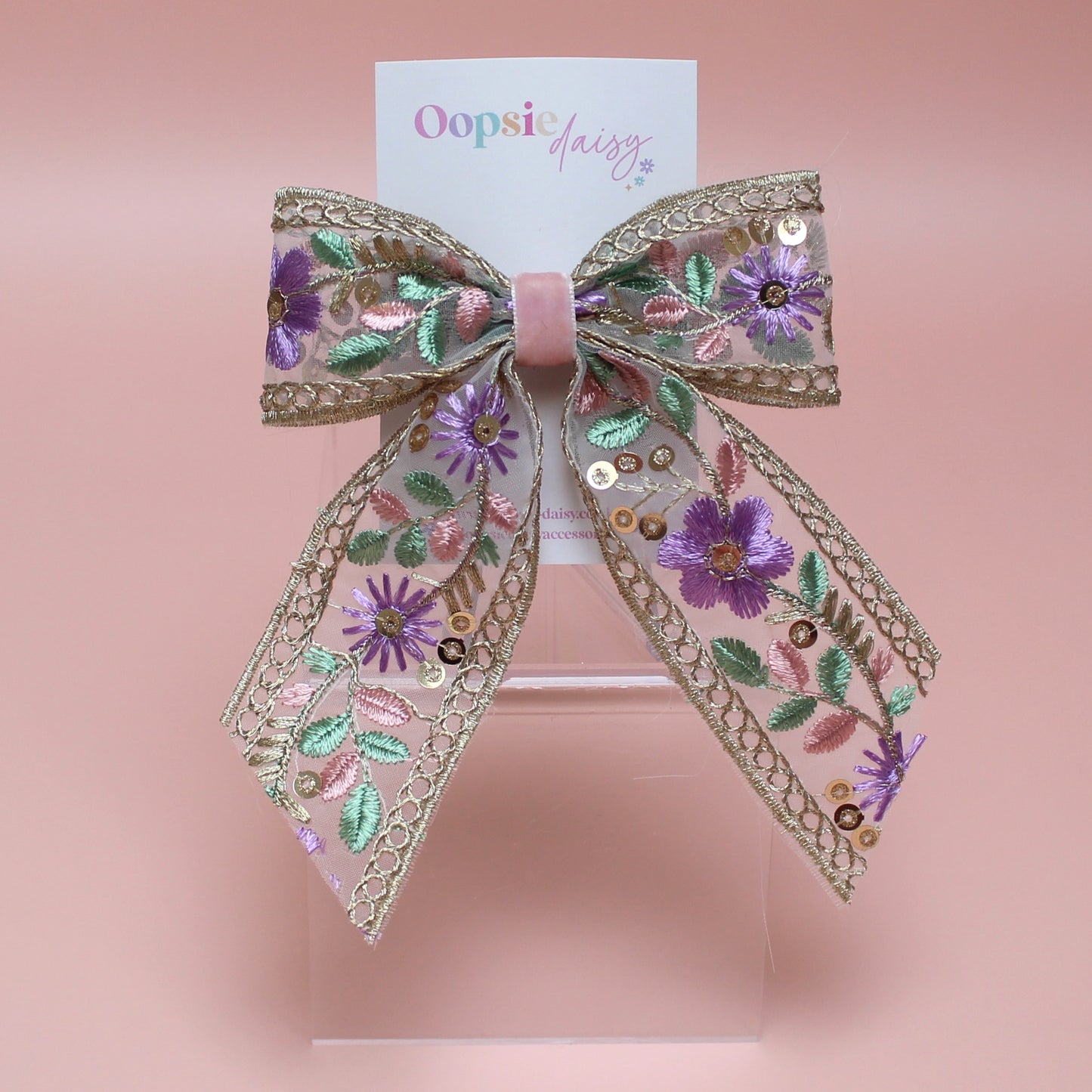 Embroidered hair bow with pink and purple flowers and gold sequins. 