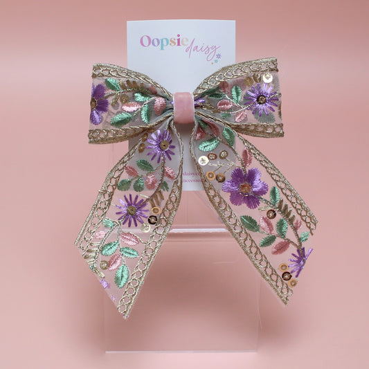 Embroidered hair bow with pink and purple flowers and gold sequins. 