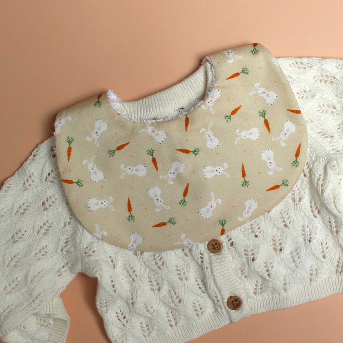 baby bib with rabbit and carrot pattern on beige background