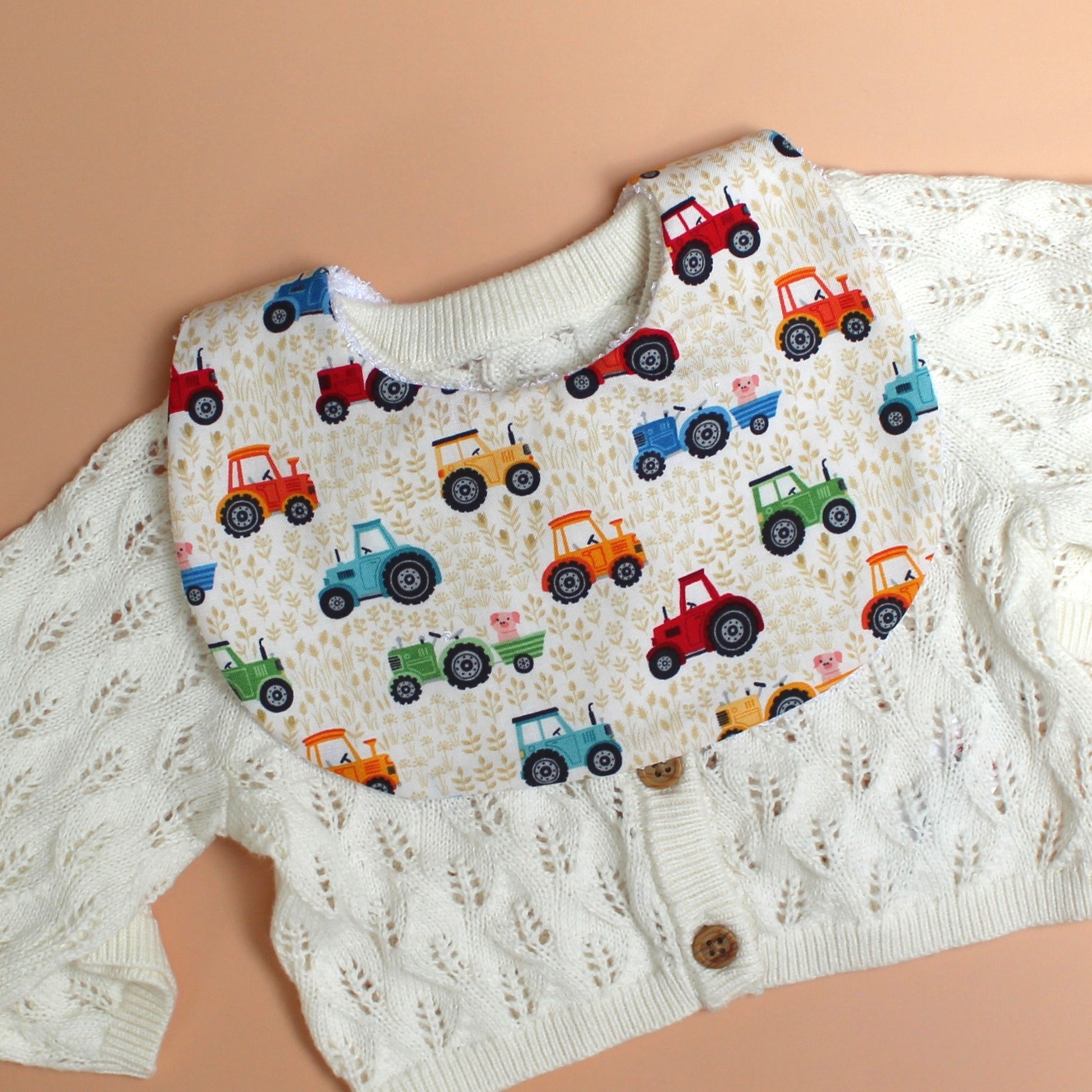 Tractor themed baby bib with colourful design and little pigs