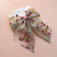 Transparent hair bow with colourful burgundy and gold embroidered floral pattern