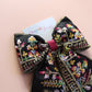 Black hair bow with colourful burgundy and gold embroidered floral pattern