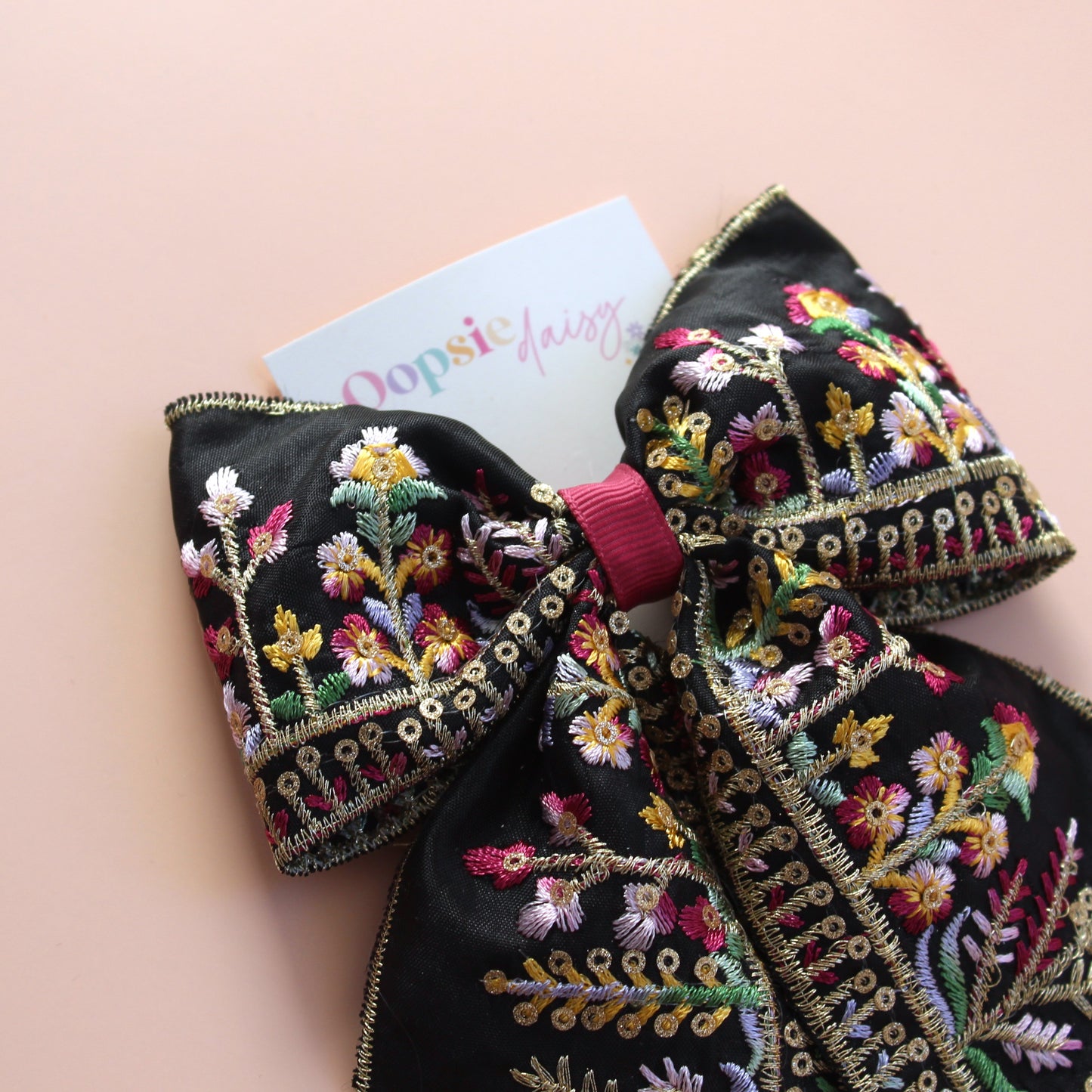 Black hair bow with colourful burgundy and gold embroidered floral pattern