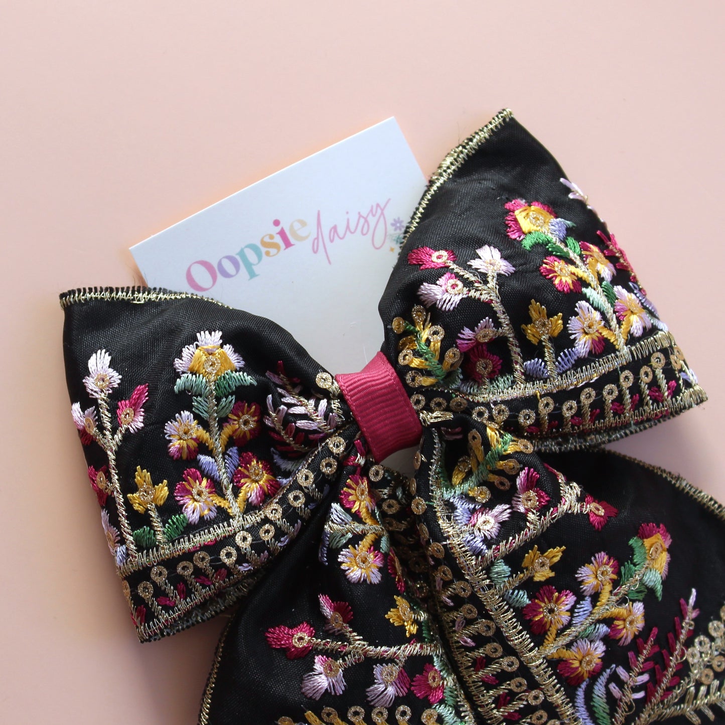 Black hair bow with colourful burgundy and gold embroidered floral pattern