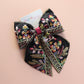 Black hair bow with colourful burgundy and gold embroidered floral pattern