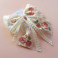 Sheer lace hair bow with cream and pink embroidered flowers