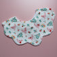 A scalloped-edge fabric bib laid flat on a pink background. The white fabric features a colourful print of pink chickens, red strawberries, and green and blue flowers.